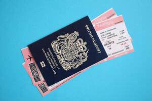 Blue British passport with airline tickets on blue background close up photo