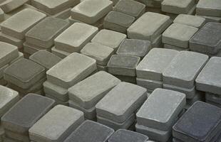 Pile of gray and dark grey walkway slab lying down outdoor. Material for Paving Slabs by mosaic close-up. Cobblestone production photo