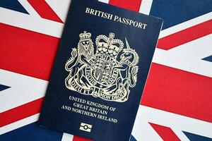 Blue British passport on national flag background close up photo