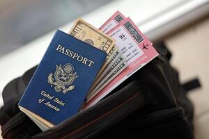 Blue United States of America passport with money and airline tickets on touristic backpack photo