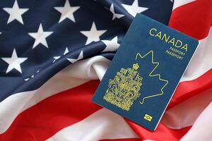 Canadian passport on United States national flag background close up. Tourism and diplomacy photo