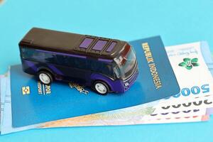 Blue Republic Indonesia passport with money and toy bus on blue background close up photo