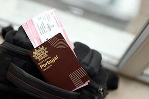 Red Portugal passport of European Union with airline tickets on touristic backpack photo