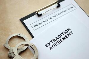 Extradition Agreement and Order Regarding Extradition with handcuffs on table photo