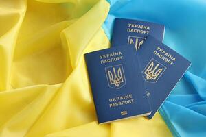 Three Ukrainian biometrical passports on folded waving flag of Ukraine country photo