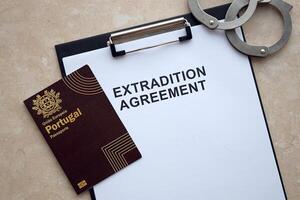 Passport of Portugal and Extradition Agreement with handcuffs on table photo