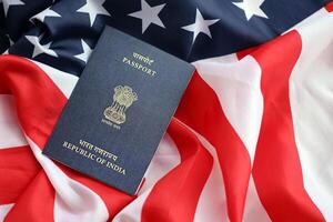 Blue Indian passport on United States national flag background close up photo