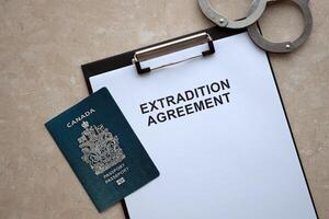 Passport of Canada and Extradition Agreement with handcuffs on table photo