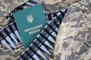 Ukrainian military ID on fabric with texture of pixeled camouflage. Cloth with camo pattern in grey, brown and green pixel shapes with Ukrainian army personal token photo