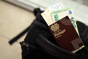 Red Portugal passport of European Union with money and airline tickets on touristic backpack photo