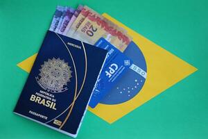 Passport book of Federative Republic of Brazil, CPF taxpayer card and brazilian reais money bills photo