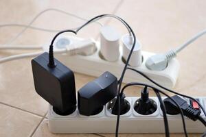 Overloaded power boards. Power strips with different electrical plugs on white floor photo