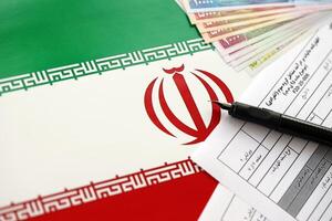 Iranian annual income tax return form F20-25-006 ready to fill on table with pen and iranian money on flag photo