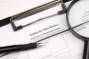 I-130 Petition for alien relative blank form on A4 tablet lies on office table with pen and magnifying glass photo