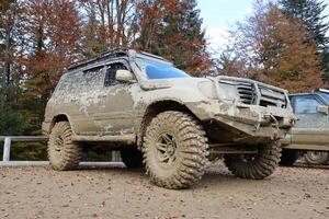 Automobile in a countryside landscape with a mud road. Off-road 4x4 suv automobile with ditry body after drive in muddy road photo