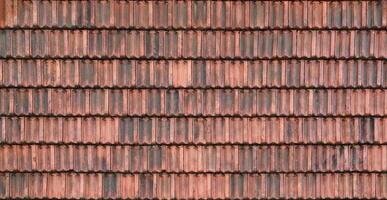 Close up of red terracotta roof shingles with some mildew. Background texture of roofing material photo