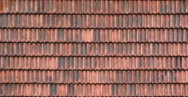 Close up of red terracotta roof shingles with some mildew. Background texture of roofing material photo