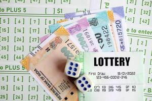 Green lottery tickets and indian rupees money bills on blank with numbers for playing lottery photo