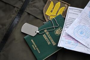 Military token or army ID ticket with mobilization notice lies on green ukrainian military uniform photo