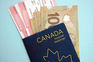 Canadian passport with money and airline tickets on blue background close up photo