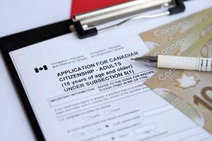 Application for Canadian citizenship for adults on table with pen and dollar bills photo