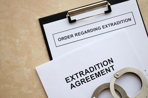 Extradition Agreement and Order Regarding Extradition with handcuffs on table photo