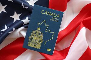 Canadian passport on United States national flag background close up. Tourism and diplomacy photo