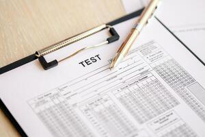 Blank educational test for students lies on table in classroom with pen photo