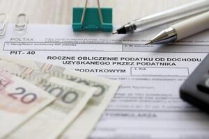 Annual calculation of tax on income obtained by taxpayer, PIT-40 tax forms on accountant table with pen and polish zloty money bills photo