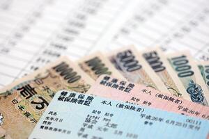 Light blue and red Japan Health Insurance cards on table with japanese yen money photo