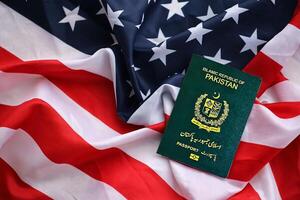 Green Islamic Republic of Pakistan passport on United States national flag background close up photo