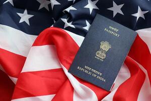 Blue Indian passport on United States national flag background close up photo