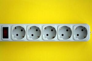 White electrical multi plug extender with european socket on bright yellow background photo