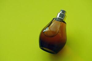 Women fragrance perfume bottle on yellow background close up. Unnamed blank sprayer bottle of perfume photo