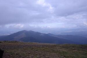 Morning view from the Dragobrat mountain peaks in Carpathian mountains, Ukraine. Cloudy and foggy landscape around Drahobrat Peaks photo