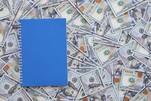 Office workplace table with blank notebook or notepad and many hundred dollar bills photo