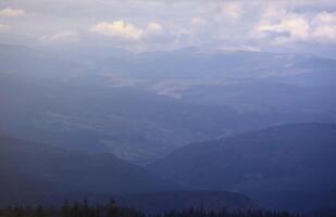 Morning view from the Dragobrat mountain peaks in Carpathian mountains, Ukraine. Cloudy and foggy landscape around Drahobrat Peaks photo