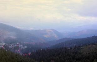 Morning view of residental area and houses around the Dragobrat mountain peaks in Carpathian mountains, Ukraine. Cloudy and foggy landscape around Drahobrat Peaks photo