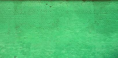 The texture of the brick wall of many rows of bricks painted in green color photo