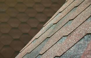 The texture of the roof with bituminous coating. Rough bituminous mosaic of red and brown flowers. Waterproof roofing photo