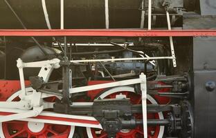 ruedas de la vieja locomotora de vapor negra de la época soviética. el lado de la locomotora con elementos de la tecnología giratoria de trenes antiguos foto