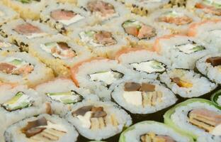 Close-up of a lot of sushi rolls with different fillings. Macro shot of cooked classic Japanese food. Background image photo