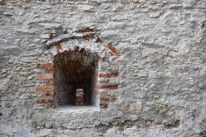 Very old window in brick stone wall of castle or fortress of 18th century. Full frame wall with window photo