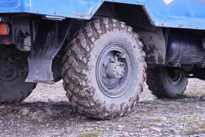 Wheel closeup in a countryside landscape with a mud road. Off-road 4x4 suv automobile with ditry body after drive in muddy road photo