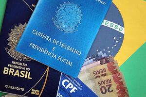 Passport of Brazil, CPF taxpayer card and work card with brazilian reais money bills on flag photo