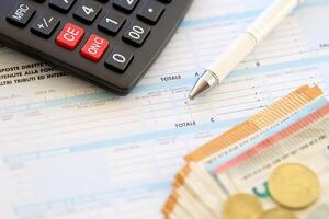 Filling italian tax form process with pen, calculator and euro money bills close up. Tax paying period photo