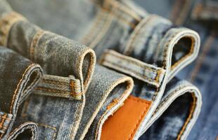 Many jeans in stack in wardrobe room. Row of pants denim jeans in closet. Concept of buy, sell, shopping and fashionable clothes photo