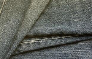 Detailed abstract texture of dark blue denim cloth. Background image of old used denim trousers fabric photo