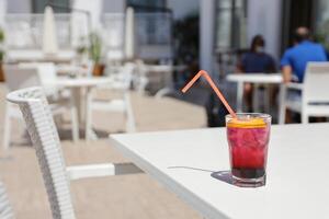 Pink and red Fresh colorful exotic alcoholic cocktail with lemon and ice on restaurant table. Colorful pink Soft drink with ice photo