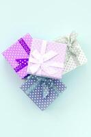 Pile of a small colored gift boxes with ribbons lies on a violet background. Minimalism flat lay top view photo